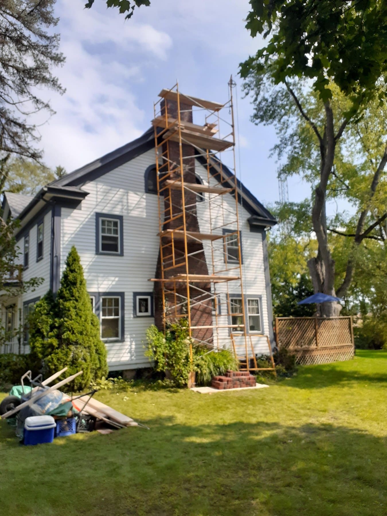 Residential house with white siding and metal scaffolding tower for chimney repair work