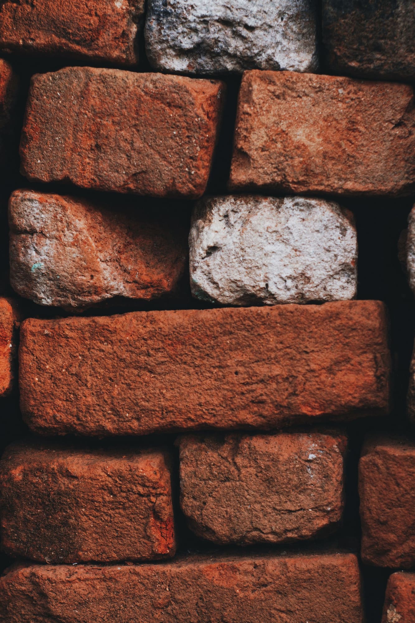 Close-up of red brick wall with mortar joints and one light-colored brick