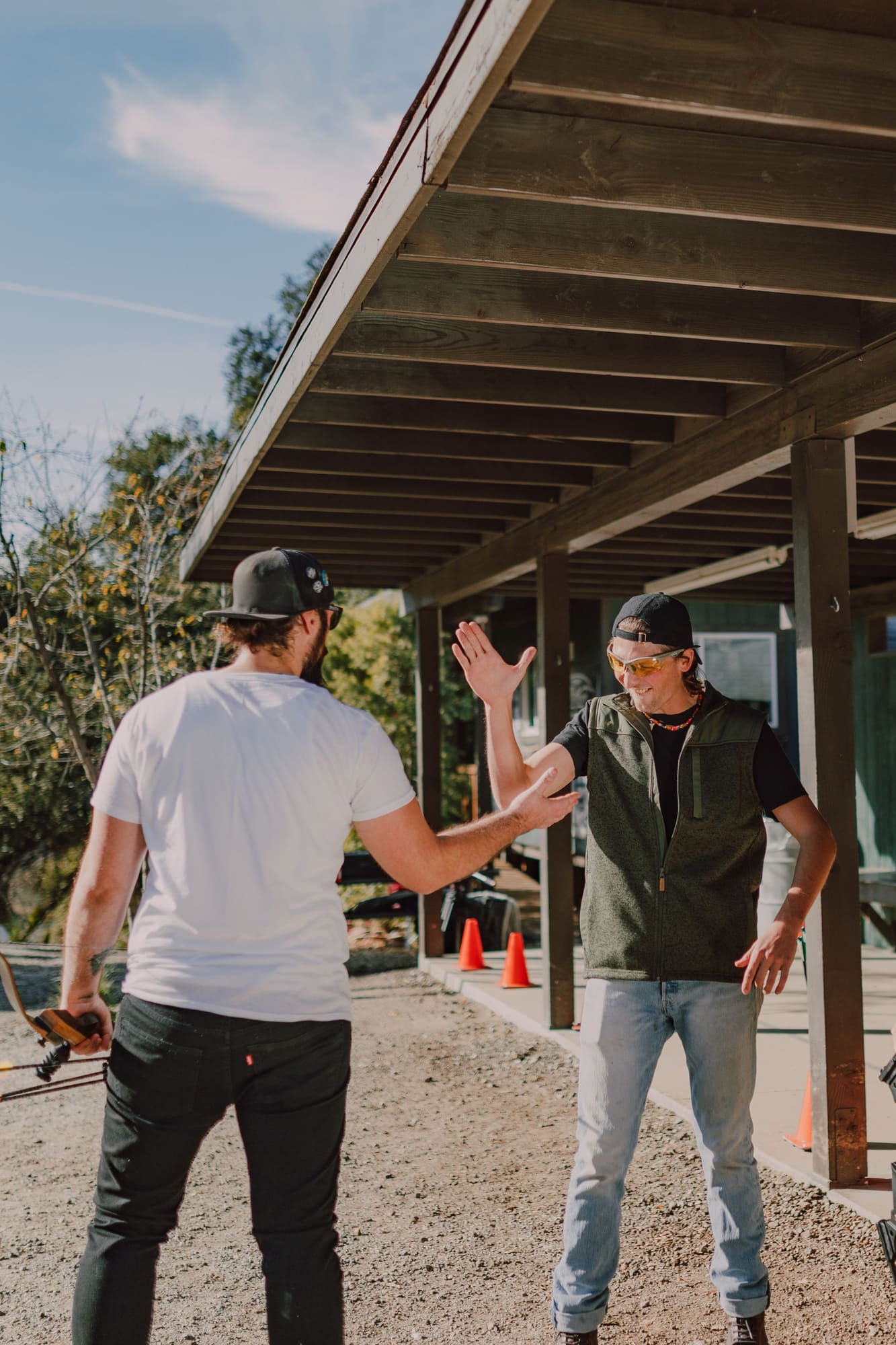 Two construction workers giving a high-five under a wooden pergola on a job site