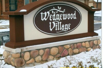 Wedgewood Village wooden sign with stone base in winter setting