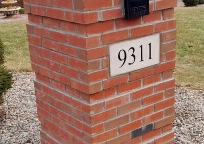 Red brick mailbox post displaying address number 9311